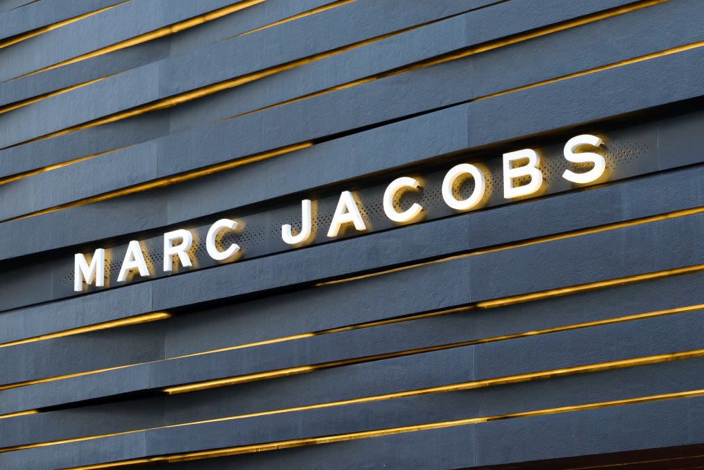 Marc Jacobs flagship storefront — backlit signage on dark stone facade with gold accent rails
